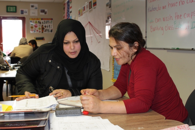 Farzaneh (right) got a full-time job, but returns to English class to help others. "We are learning together", she says.